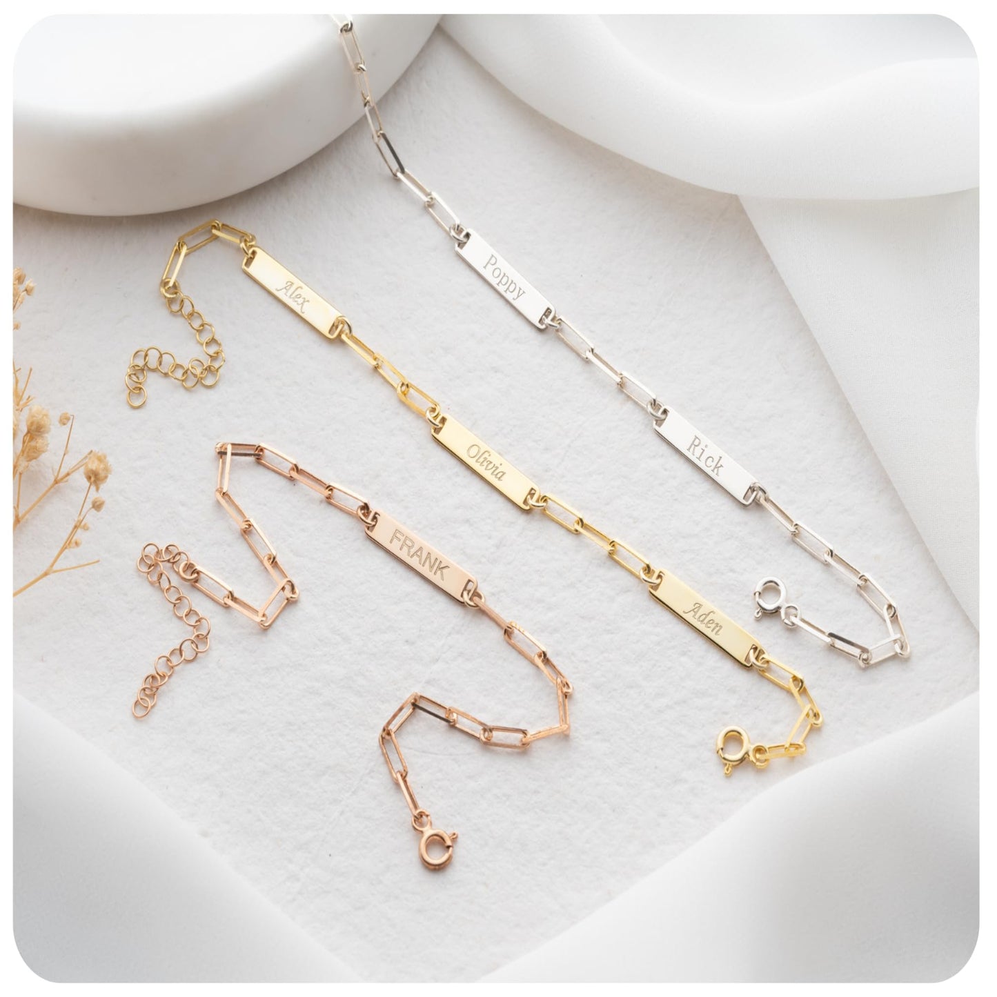 Gold and rose gold bracelets on a white surface with small flowers.