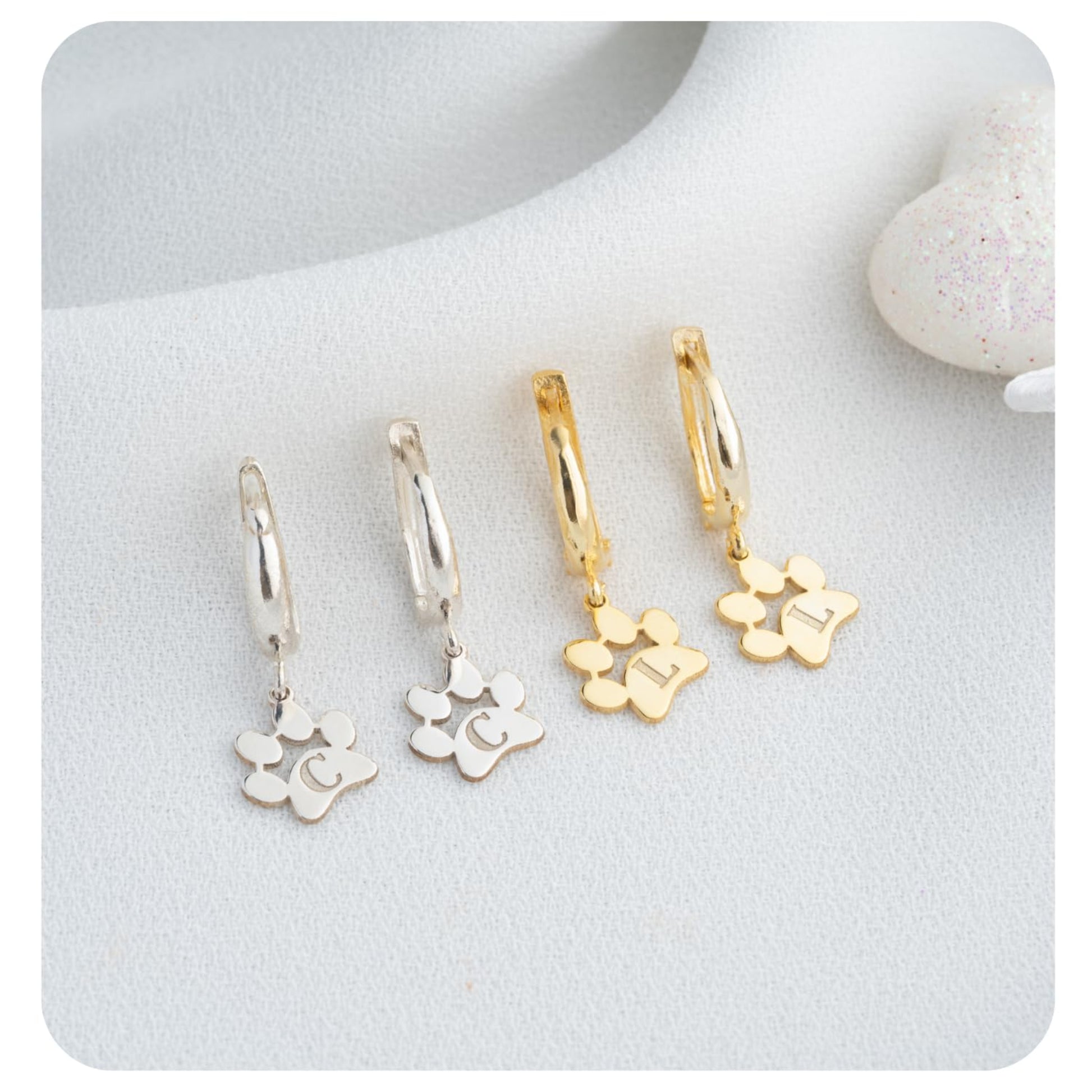 Set of gold and silver hoop earrings with floral charms on a white surface.