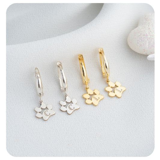 Set of gold and silver hoop earrings with floral charms on a white surface.