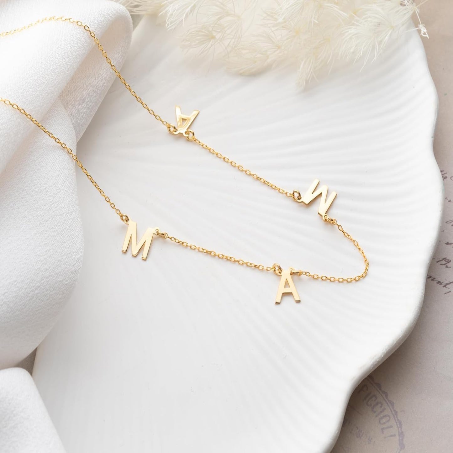 Gold necklace with letter pendants on a white surface
