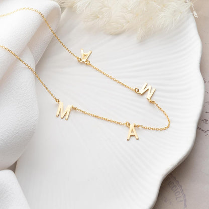 Gold necklace with letter pendants on a white surface