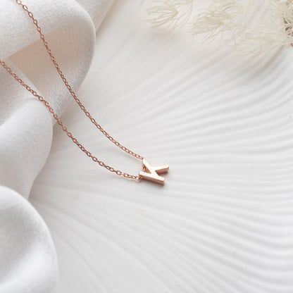 Rose gold necklace with a small pendant on a soft white fabric background