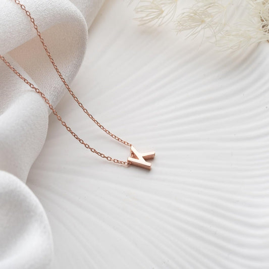 Rose gold necklace with a small pendant on a soft white fabric background