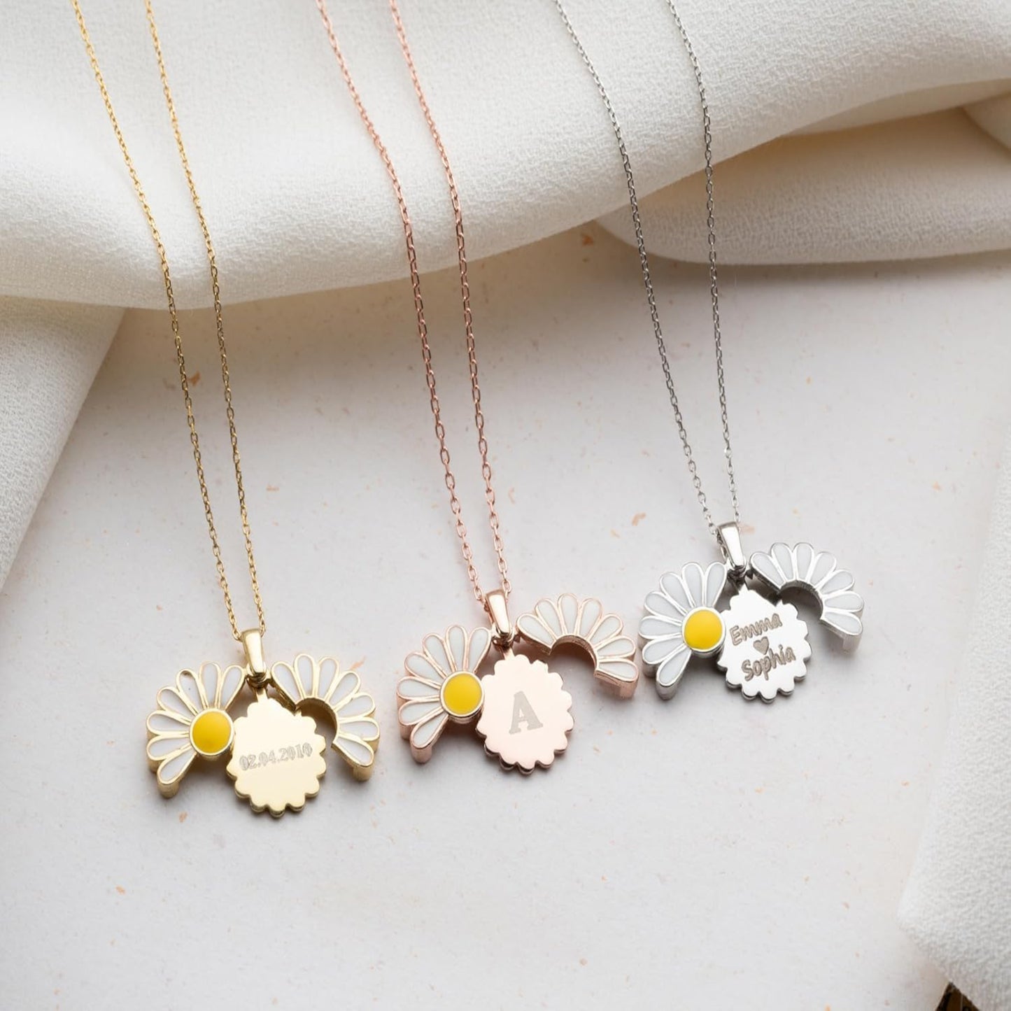 Three floral necklaces with engraved names on a light fabric background
