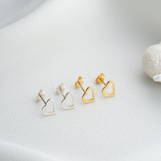 Heart-shaped earrings in gold and silver on a light gray surface