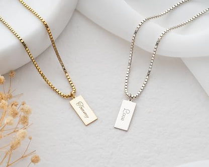 Two necklaces with engraved tags on a light background