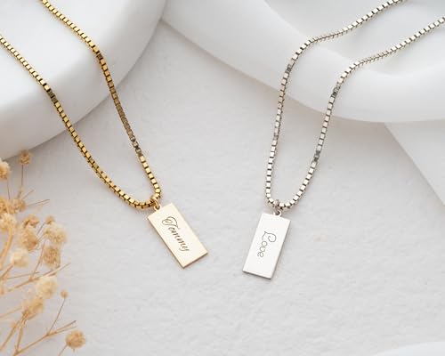 Two necklaces with engraved tags on a light background