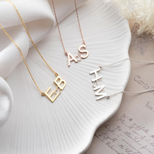Three gold necklaces with engraved names on a white dish.