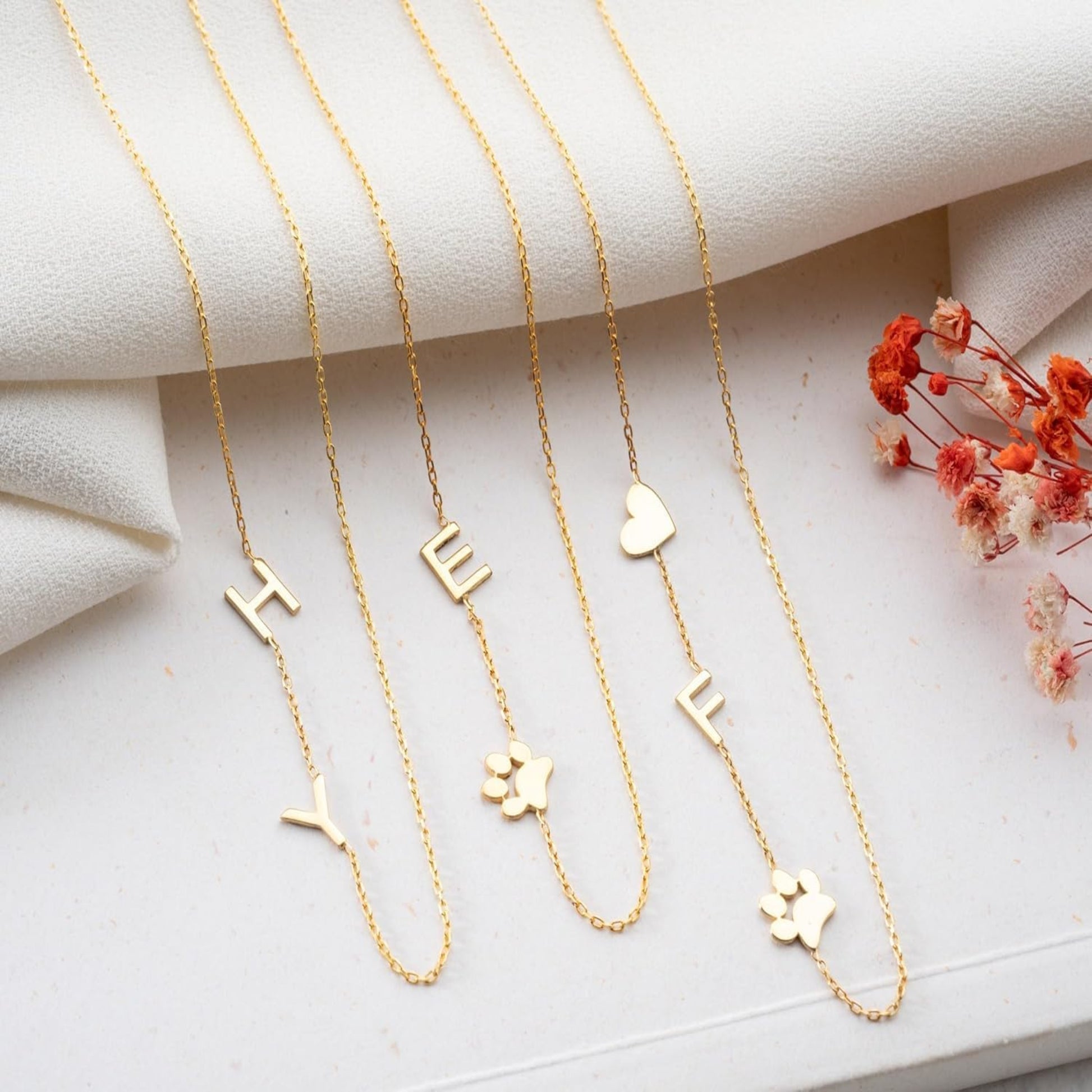 Gold necklaces with various charms on a light background