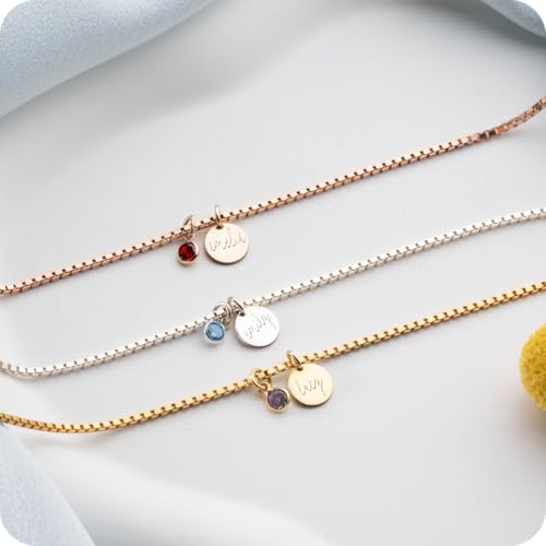 Three gold necklaces with various charms on a light gray surface