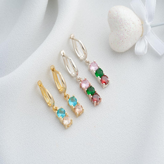 Pair of earrings with colorful gemstones on a light background