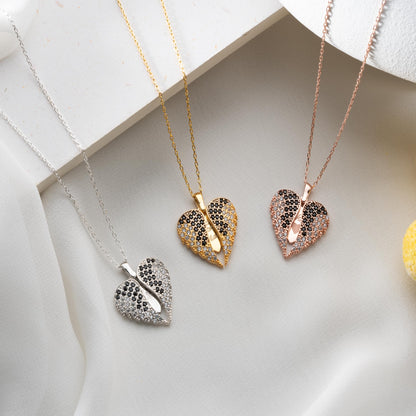 Three heart-shaped pendants on necklaces in gold, silver, and rose gold on a light background.